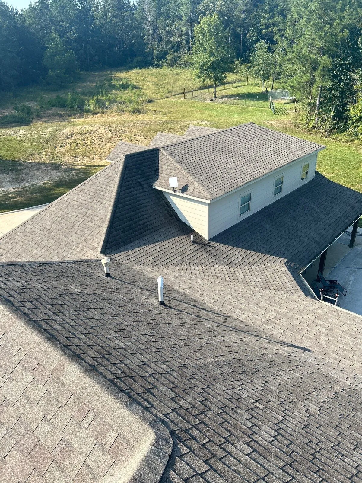 Fresh shingle field with new pipe boots seen from the ridge on a Dickerson job
