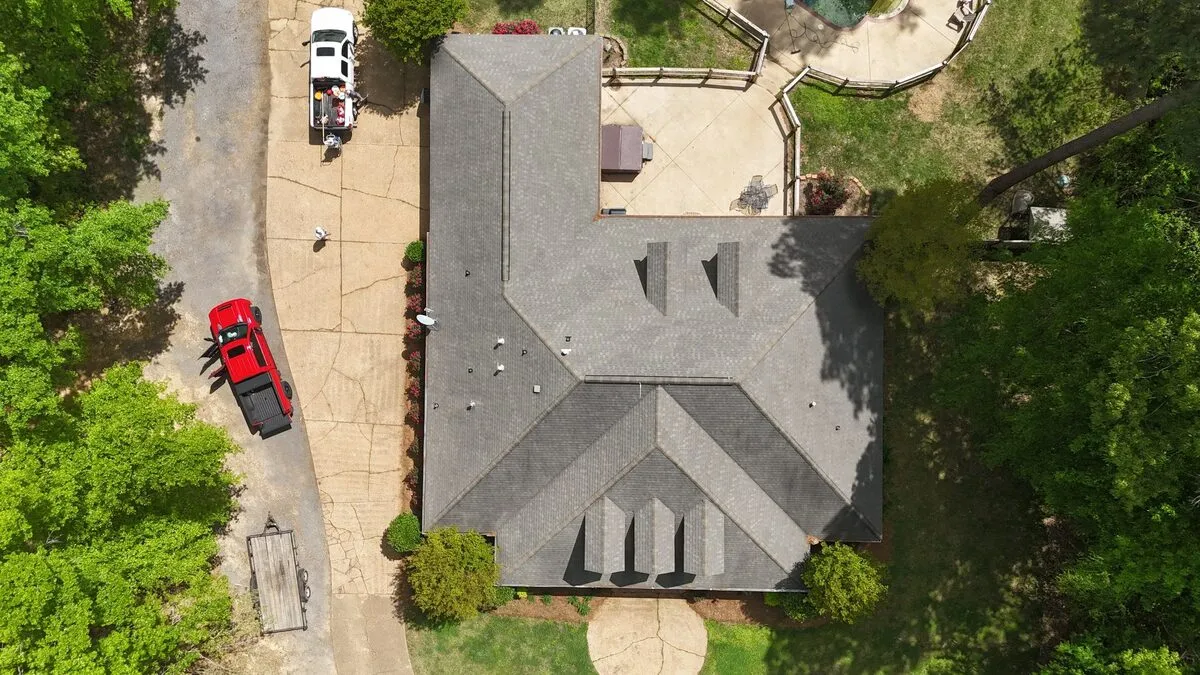 Overhead view of a completed shingle roof with Dickerson trucks staged in the driveway