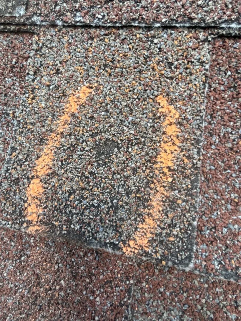 Hail impact marks chalked on a roof during storm damage inspection